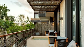 A modern outdoor seating area with a pool, wooden chairs, and a woven fence. - Bloom Tulum | Two 2-BR Apartment |  w/ Private Terrace Near Tulum Ruins (Tulum)