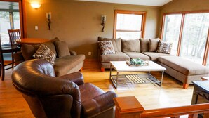 A living room with a sofa set, a coffee table, and a dining table. - Rib Mountain Cabin (Wausau)
