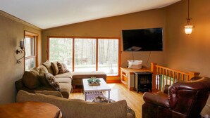 A living room with a sofa, armchair, and a flat-screen TV mounted on the wall. - Rib Mountain Cabin (Wausau)