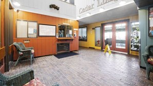En lobby med receptionsdisk, fletstole, pejs og et skilt der siger "Welcome to Cedar Lodge".
