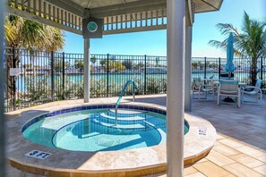 A pool area with a clock, chairs, and a view of the water. - 4th Floor Condo with Water Views (Treasure Island)