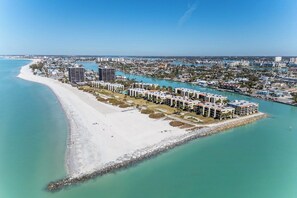An aerial view of a coastal resort with beachfront villas, a marina, and a clear blue sky. - 4th Floor Condo with Water Views (Treasure Island)