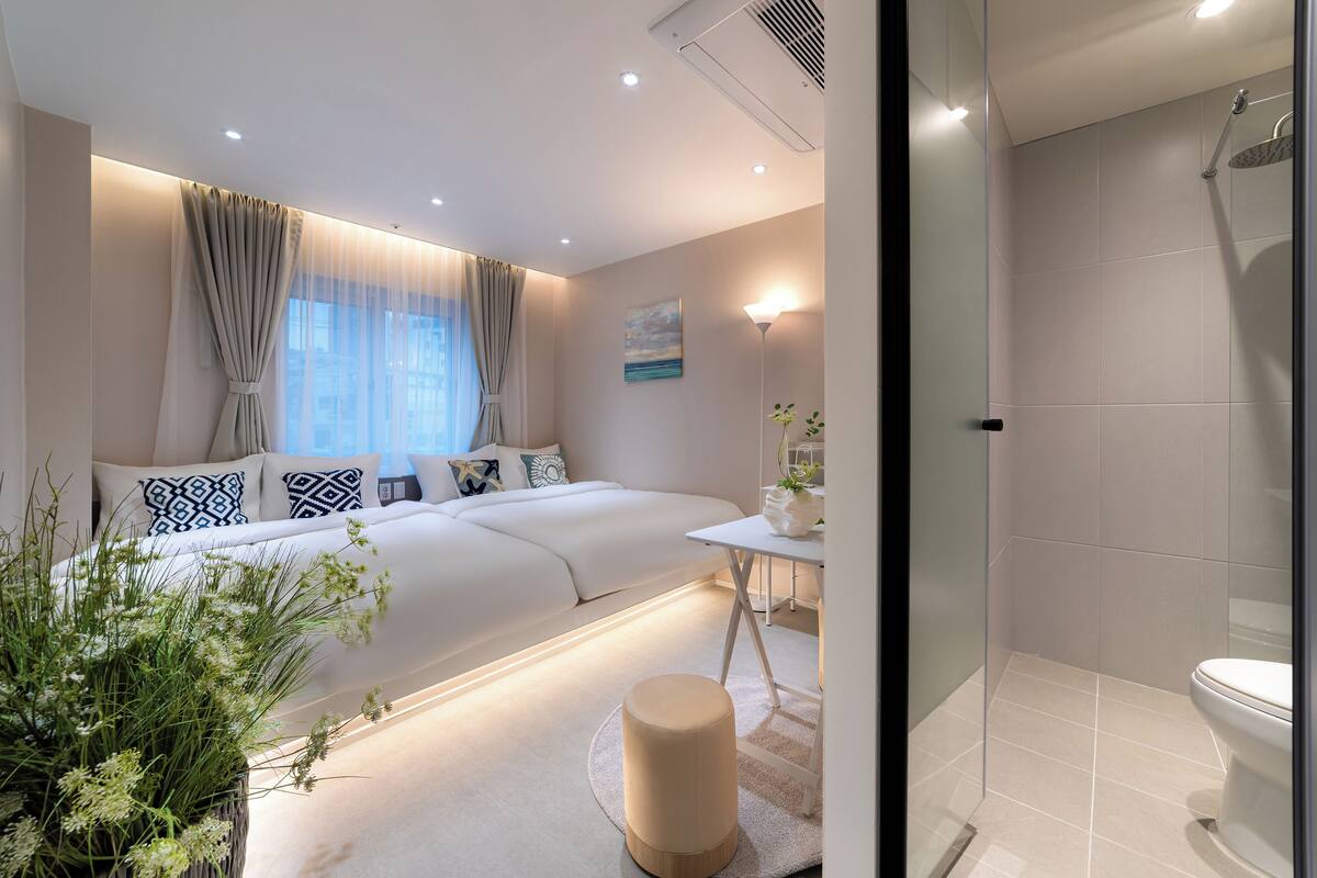 Un dormitorio moderno con una cama grande, mesita de noche y vistas a la ciudad.