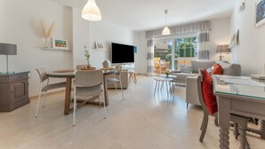 Een moderne woonkamer met een eethoek, een flatscreen televisie en een bank.