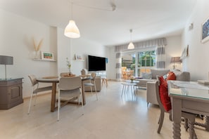 Una sala de estar moderna con comedor, televisor de pantalla plana y sofá.