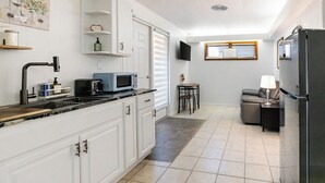 Eine moderne Küche mit weißen Schränken, einem schwarzen Kühlschrank, einer Mikrowelle und einem Essbereich mit Tisch und Stühlen.