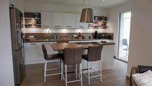 A modern kitchen with a central island, stainless steel appliances, and a large window providing natural light.