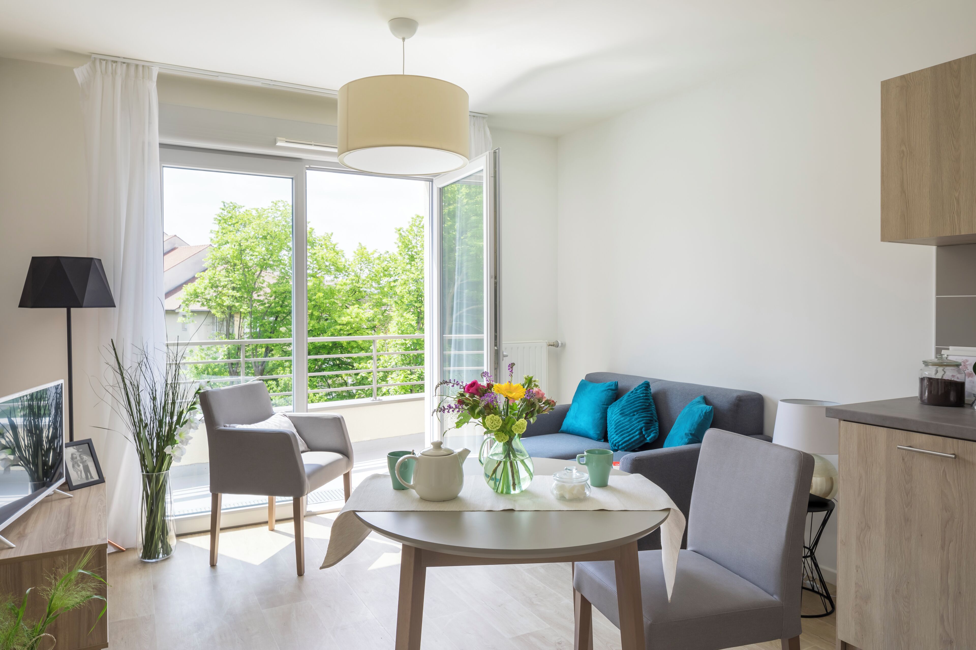 A modern living room with a sofa, chairs, a dining table, and a kitchen area.