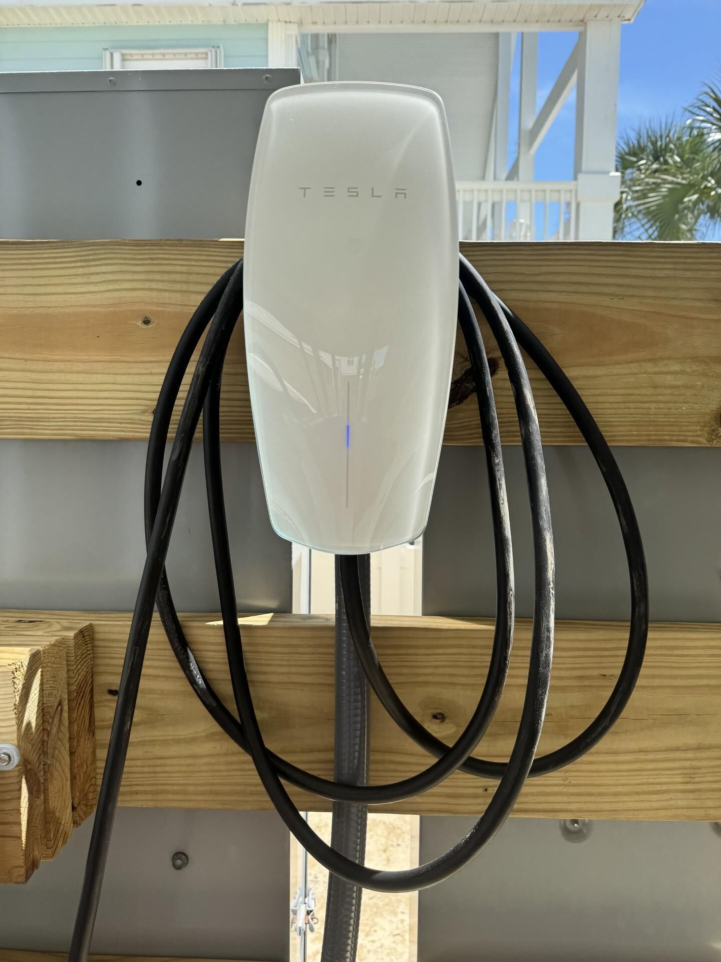 A Tesla charging station with a wooden structure in the background.