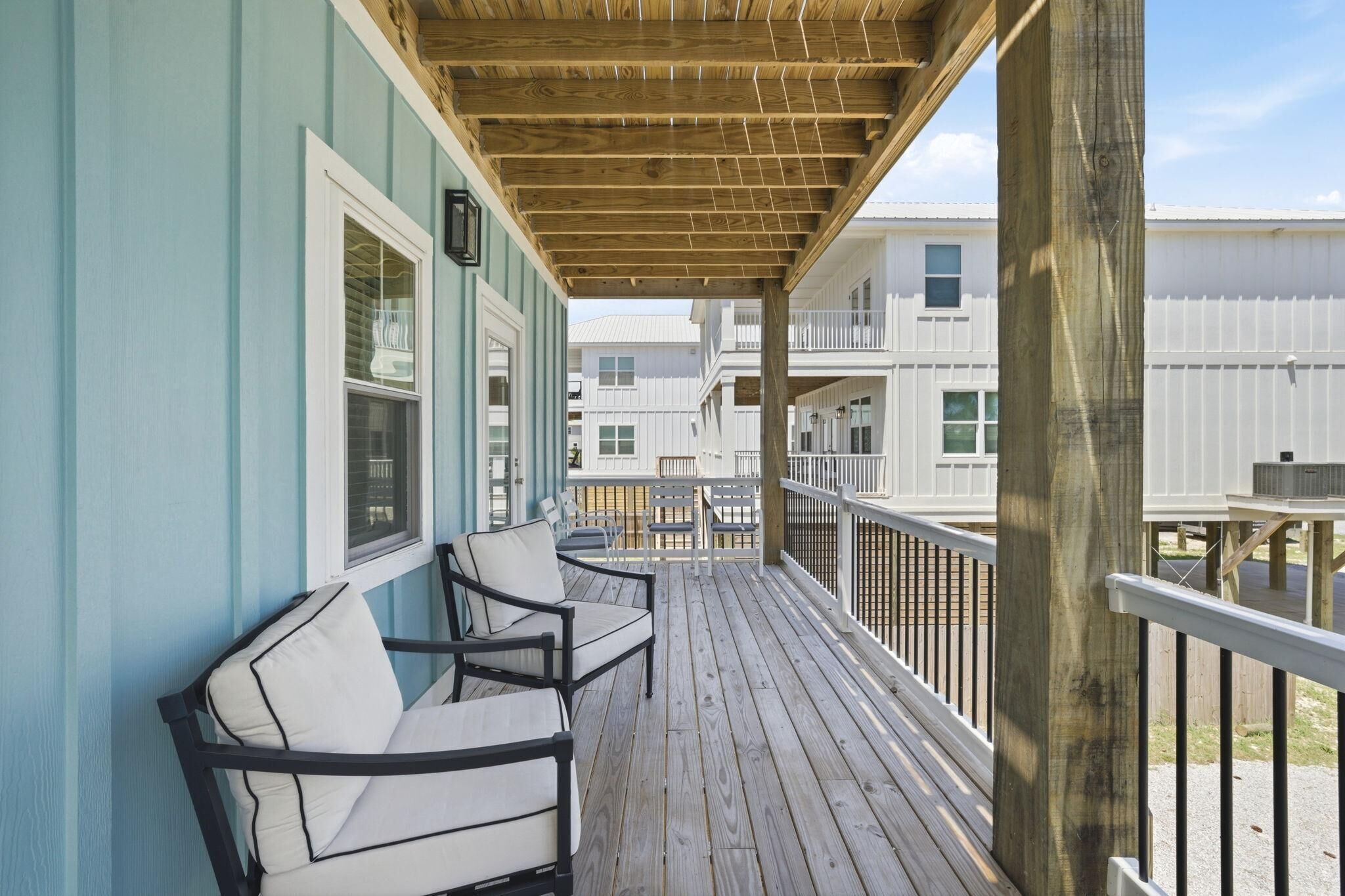 A wooden deck with two chairs, a small table, and a railing.