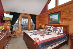 A wooden cabin bedroom with a bed, a TV, a desk, and a chair. - Spectacular 4BR Cabin w/ Game Room, Hot Tub, Views (Gatlinburg)