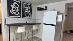 A modern kitchen with a white refrigerator, two white bar stools, and abstract wall art. - Beautiful 2-bedroom house in tranquil Warren perfect for relaxing stays (Warren)