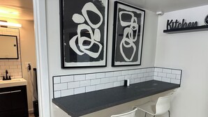 A modern kitchen with a black countertop, white chairs, and abstract art on the wall. - Beautiful 2-bedroom house in tranquil Warren perfect for relaxing stays (Warren)
