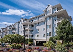 A multi-story residential building with balconies, a parking garage, and landscaped gardens.