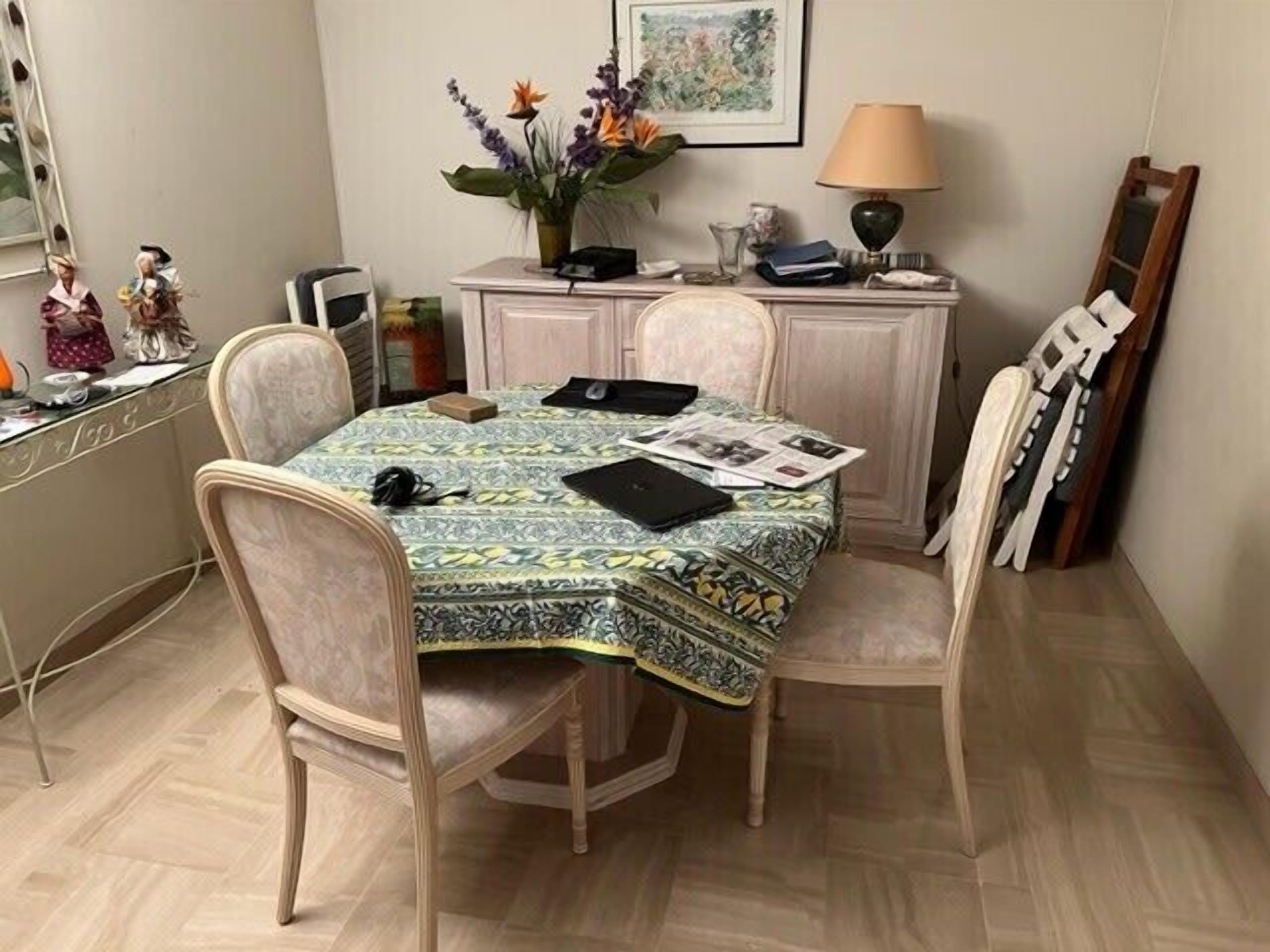 Comedor con una mesa cubierta con un mantel estampado, rodeada de cuatro sillas.