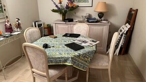Un coin repas avec une table recouverte d’une nappe à motifs, entourée de quatre chaises.