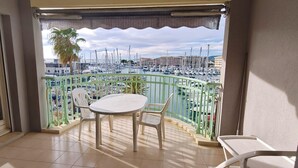 Un balcon donnant sur un port de plaisance, avec une table et deux chaises.