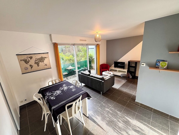 A modern living space with a dining area, a sofa, a TV, and a bookshelf.