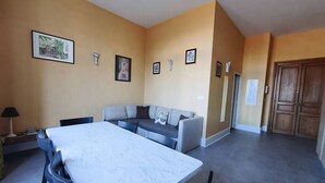Ein geräumiges Zimmer mit Esstisch, einer Couch und einem Schrank.