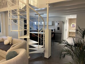 A modern interior with a spiral staircase, a kitchen area, and a seating area with a sofa and cushions. - Pamela Loft, Aix-les-Bains (Aix-les-Bains)