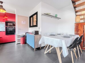 Een moderne keuken met een rode inrichting, een blauw aanrecht en een eethoek met een tafel gedekt voor vier personen.