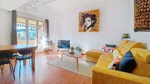 A modern living room with a yellow sofa, a dining table with chairs, a TV, and a large window with curtains. - Bel appartement à 3 min de la plage à La Ciotat (La Ciotat)