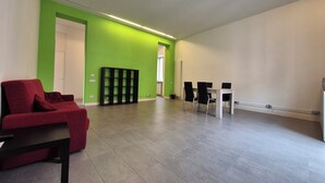 Une pièce spacieuse avec un canapé rouge, une étagère noire et une table à manger avec des chaises.
