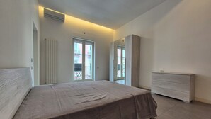 Une chambre à coucher comprenant un lit, une commode et une porte coulissante donnant sur un balcon.