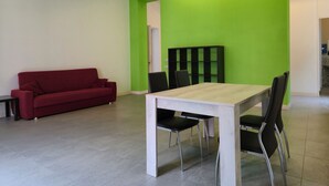 Une pièce moderne avec un canapé rouge, une table en bois et des chaises noires.