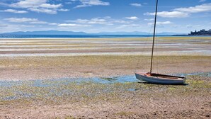 A boat on a beach with a clear sky and distant mountains. - Birch Bay | Group Beach Retreat | Pool + Beach | 2BR (Blaine)