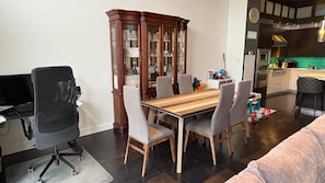 Un coin repas avec une table et des chaises en bois, un meuble avec des portes en verre, un coin cuisine et un canapé.