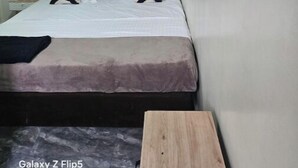 A bedroom with a bed, two wall-mounted air conditioners, a ceiling light, and two framed artworks. - Great stay (Kinshasa)