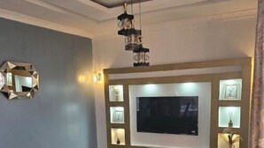 A modern living room with a large flat-screen TV, a glass coffee table, and a sofa. - Great stay (Kinshasa)