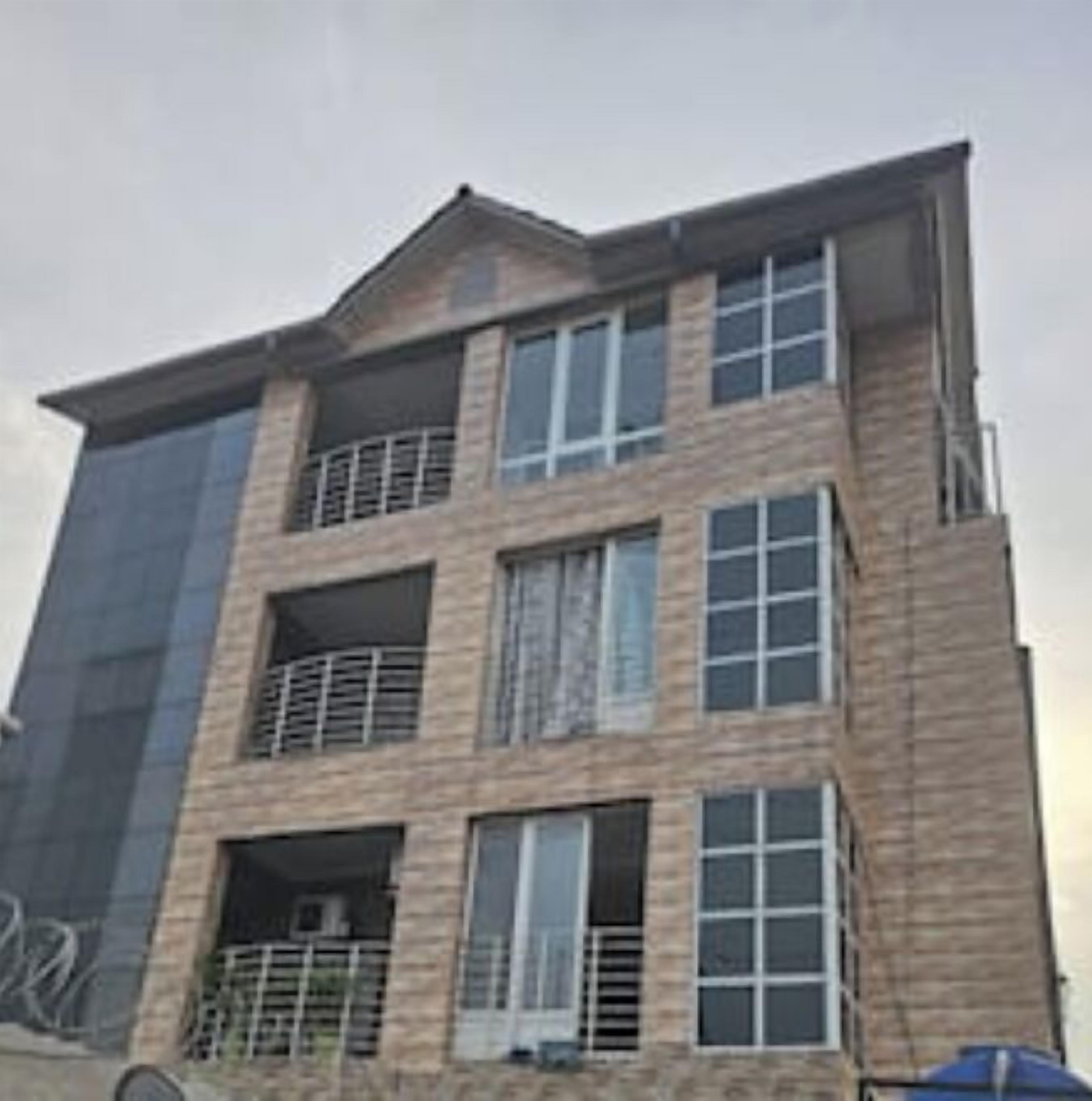 A multi-story building with a modern architectural design, featuring balconies and large windows.