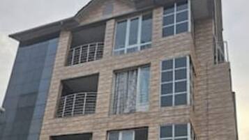 A multi-story building with a modern architectural design, featuring balconies and large windows.