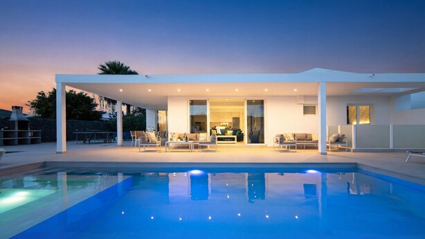 A modern house with a pool, outdoor seating, and a patio area.