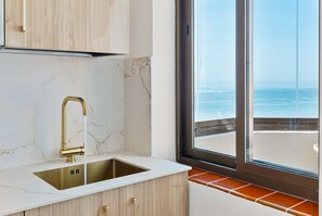 A kitchen with a marble countertop, a gold faucet, and a view of the ocean through a window. - Stunning apartment with seaviews in Fuengirola (Fuengirola)