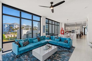 Una sala de estar moderna con un sofá seccional, una mesa de centro y ventanas amplias con vistas al exterior.