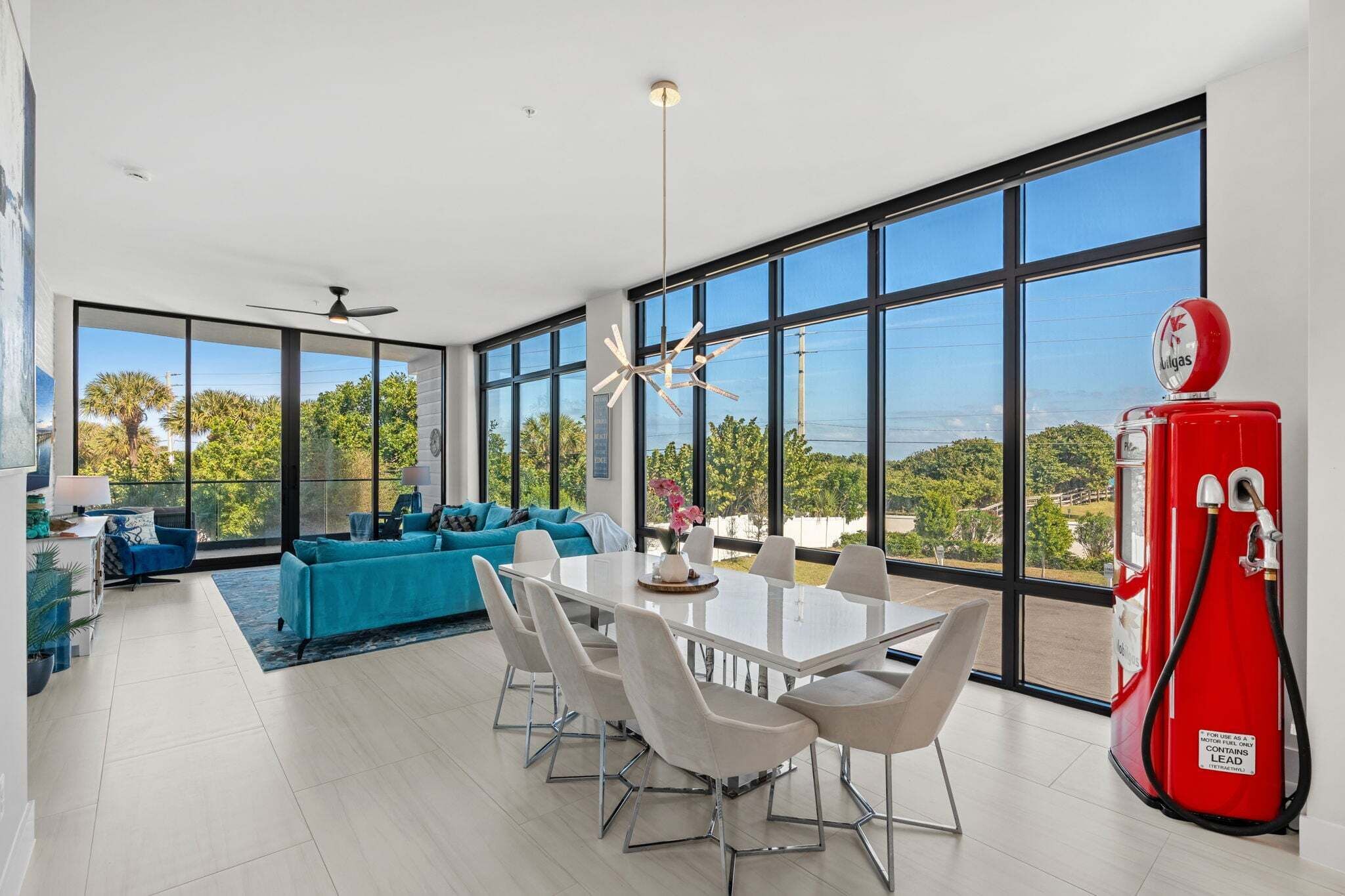 A modern living room with a dining area, large windows, and a red gas pump.