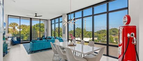 A modern living room with a dining area, large windows, and a red gas pump.