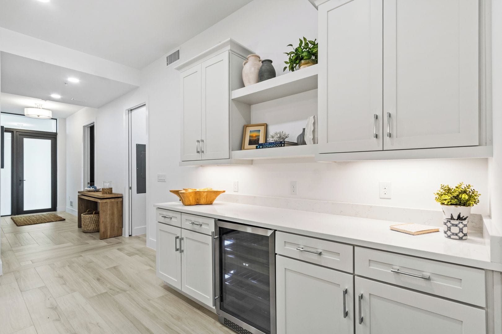 A modern kitchen with white cabinetry, a stainless steel dishwasher, and a wooden countertop.