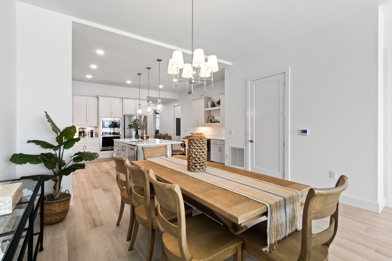 A modern kitchen with white cabinets, a central island, and pendant lighting.
