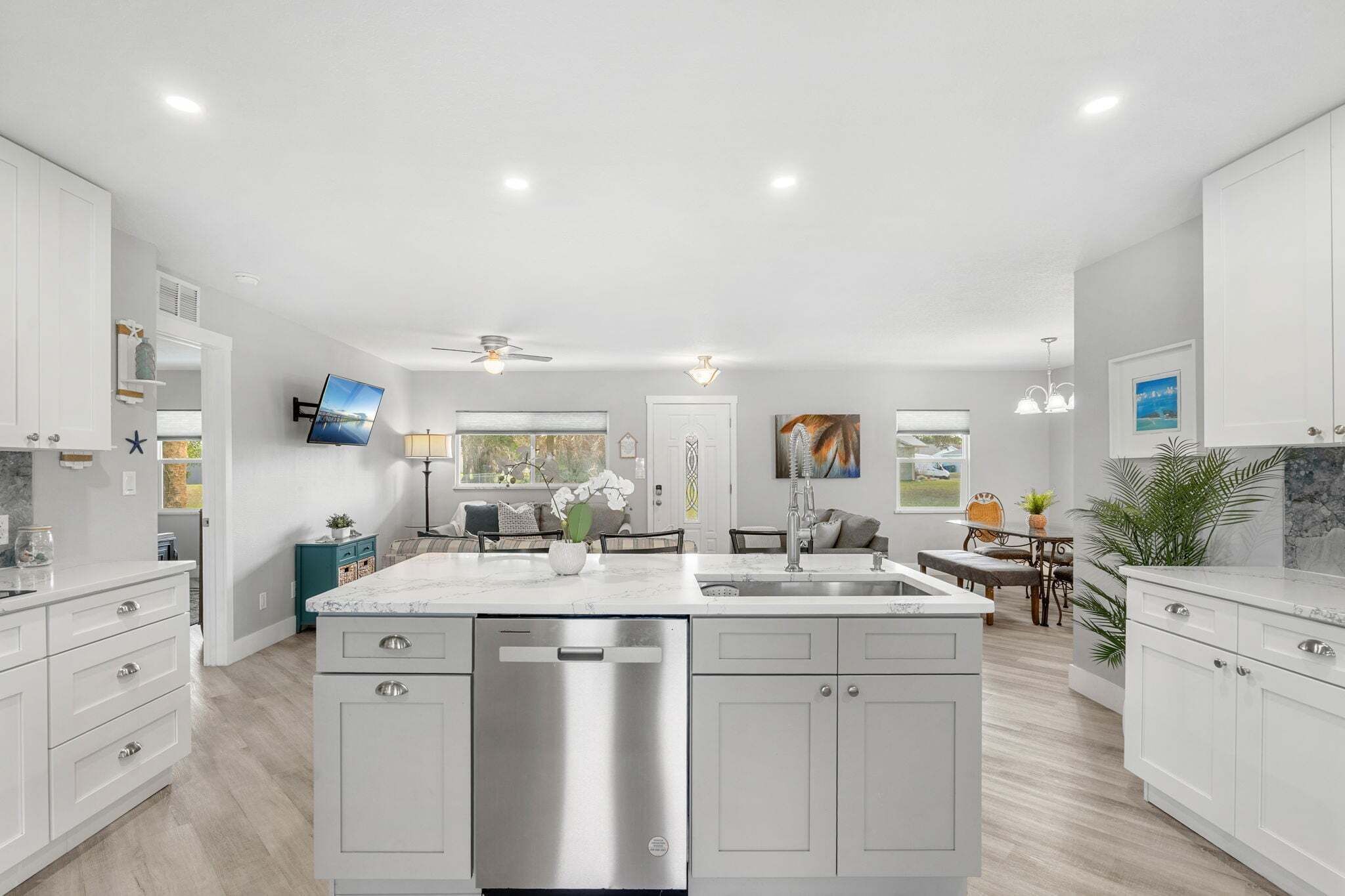 A modern kitchen with white cabinetry, a central island, and a built-in dishwasher.