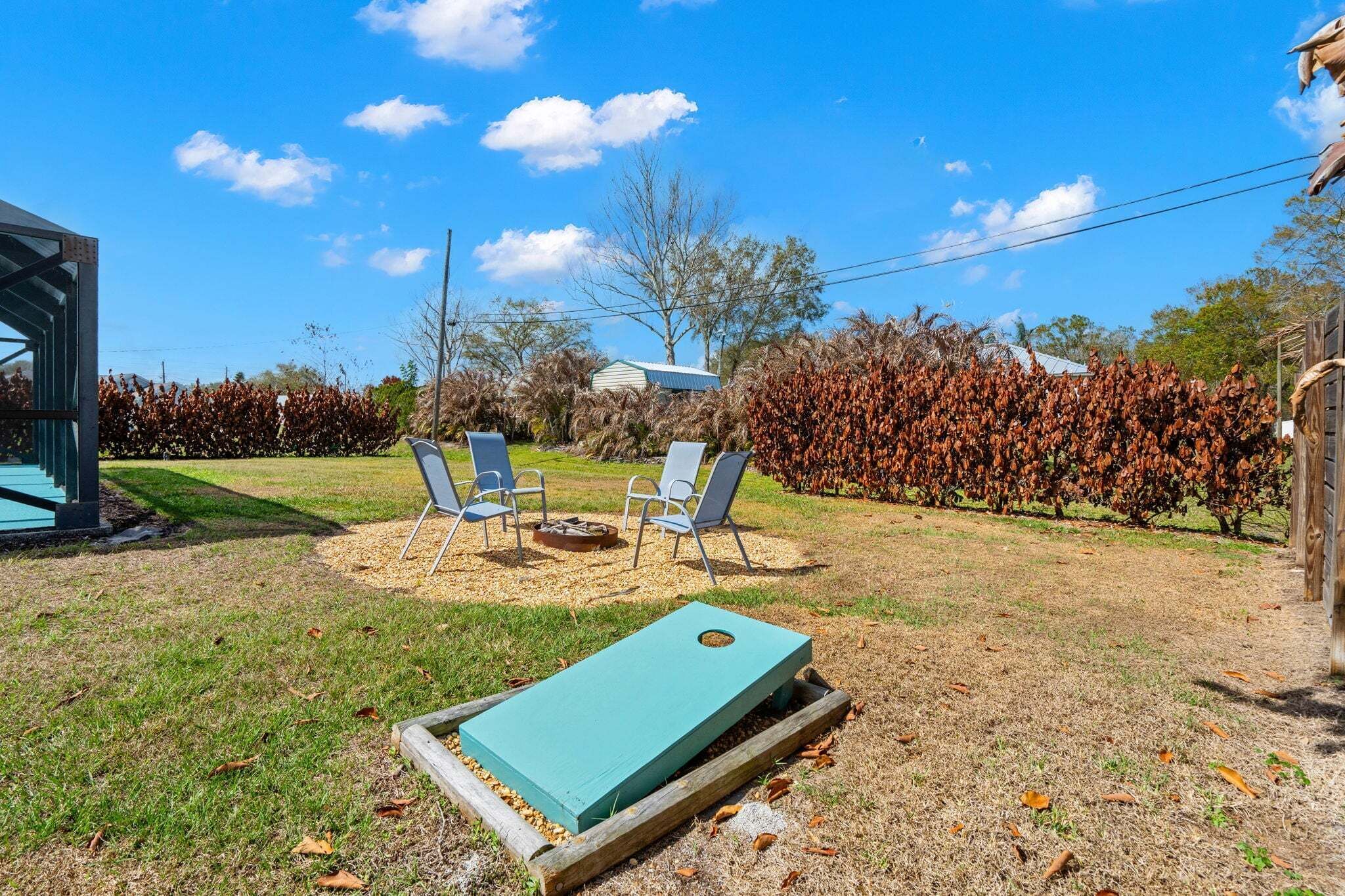 A backyard with a fire pit, two chairs, and a blue bean bag chair.
