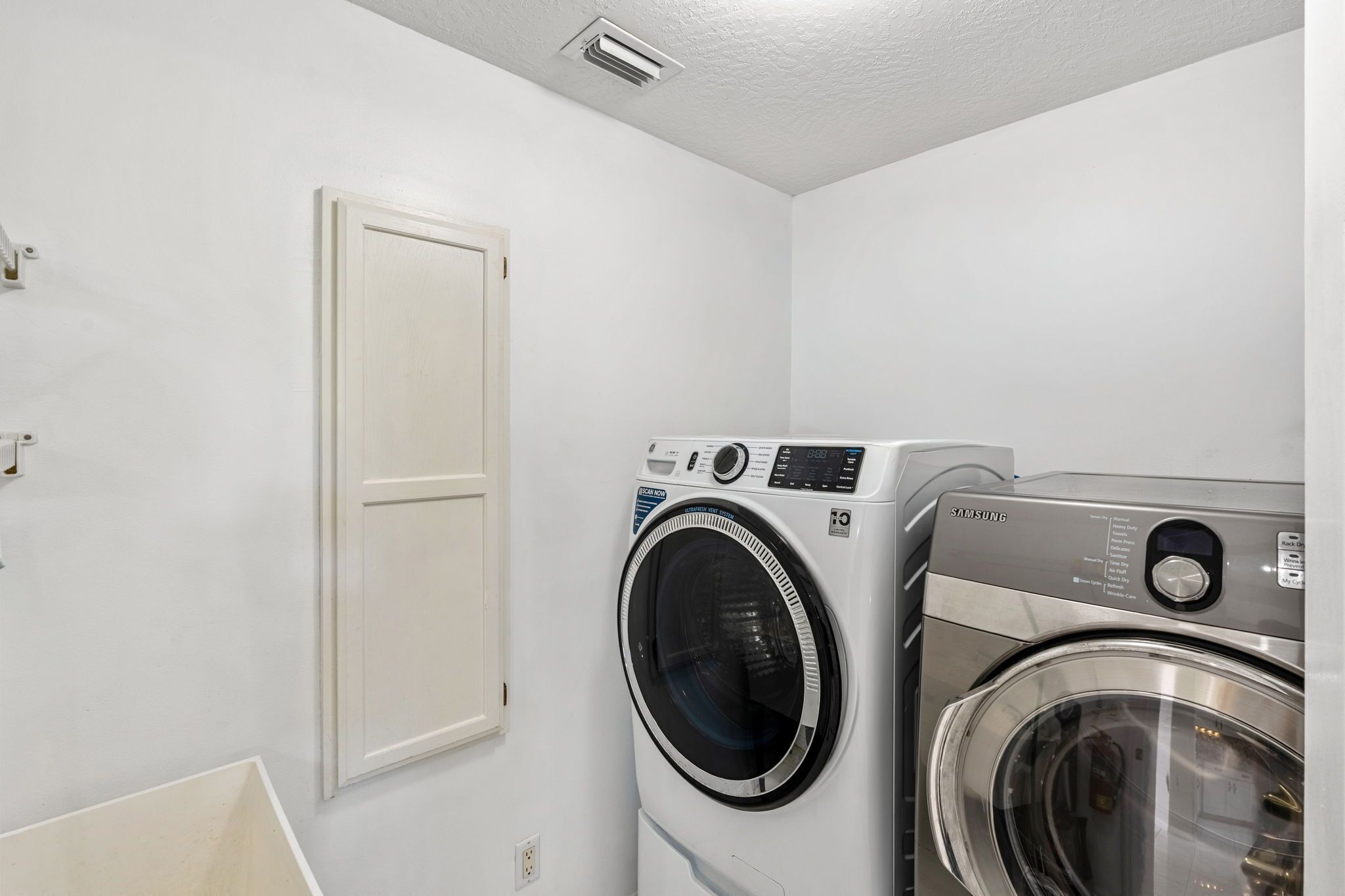A laundry room with two front-loading washing machines and a white door.