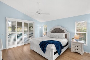 Ein Schlafzimmer mit Bett, Nachttisch, Deckenventilator und einem Fenster mit Jalousien.