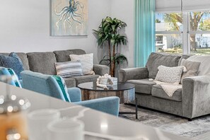 A living room with two grey sofas, a round coffee table, and a large window with a view of the outdoors. - 1544 Lime Drive (Melbourne)
