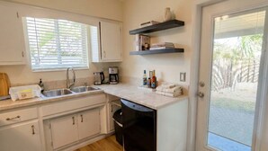 A modern kitchen with white cabinets, a dishwasher, a countertop with various items, and a ceiling fan. - Lux 3BD House, 5 Min To Holly Cross, HCA Hospital&Beaches (Oakland Park)