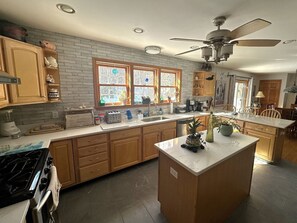 Una cocina amplia con armarios de madera, una isla central y un gran ventanal con vidrieras.
