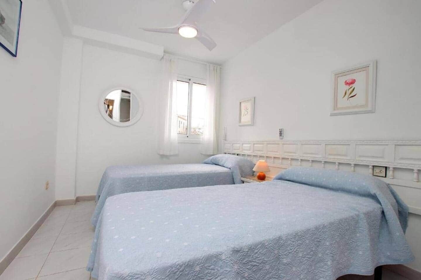 Une chambre avec deux lits, un ventilateur de plafond, une fenêtre et un miroir.